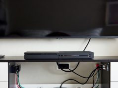 Cable Chaos Tamer: Organize Wires with Household Items Behind a TV console, cables are managed invisibly using clear adhesive hooks mounted on the furniture back.